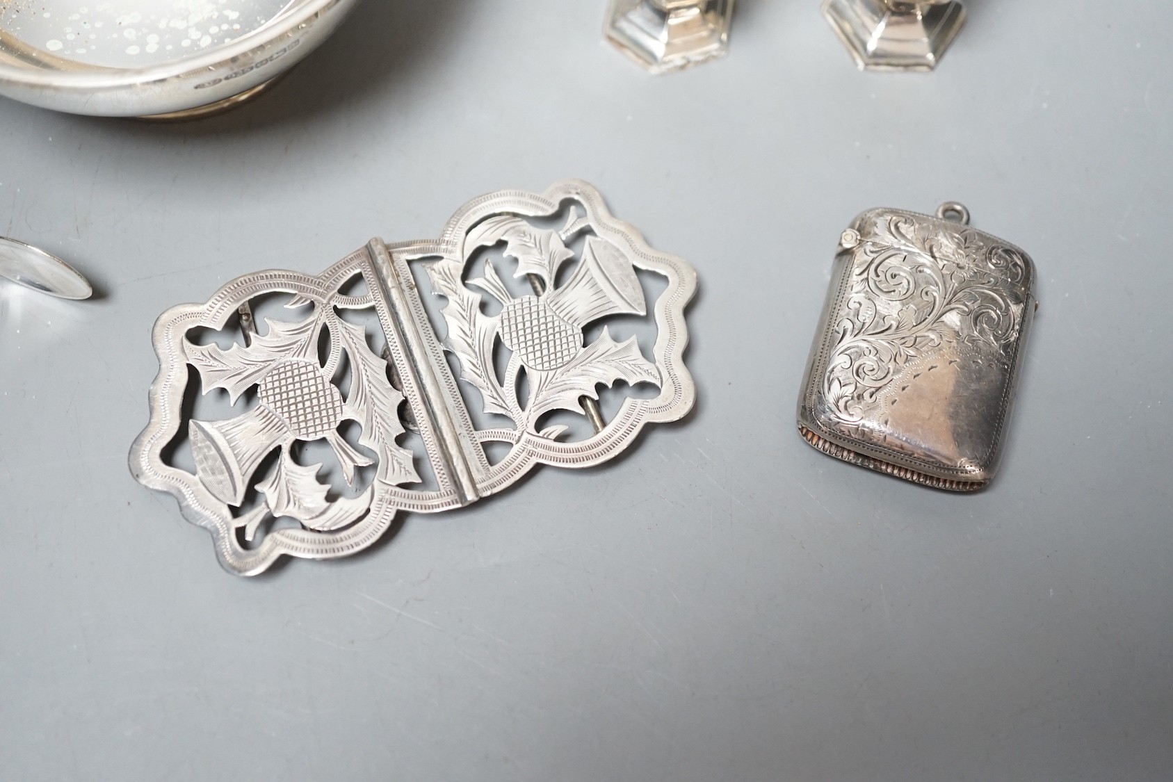 A group of assorted small silver, including a modern two handled bowl, pepperettes, vest case, belt buckle and tongs.